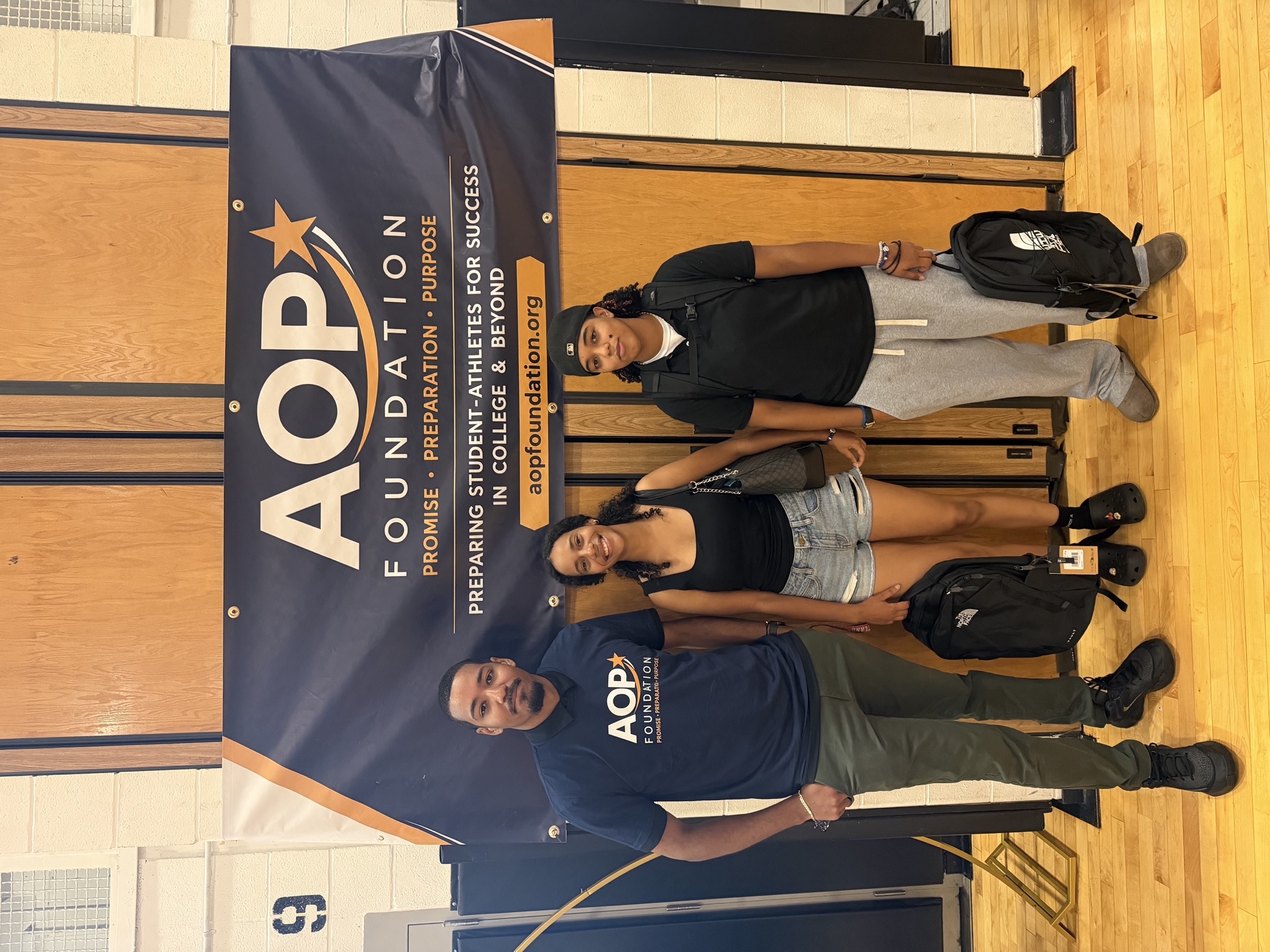 AOP staff member and two students with new backpacks at the Back-to-School Community Kickoff.